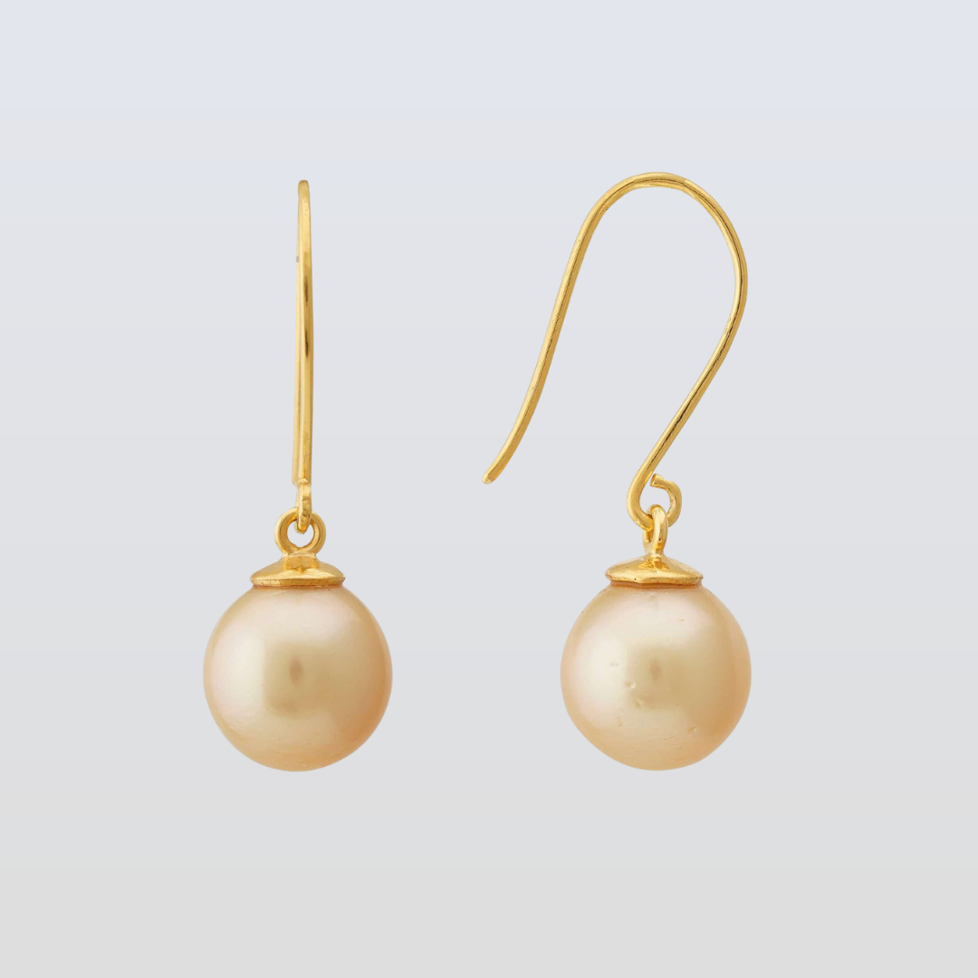 Gold earrings with pearl drops on a light gray background