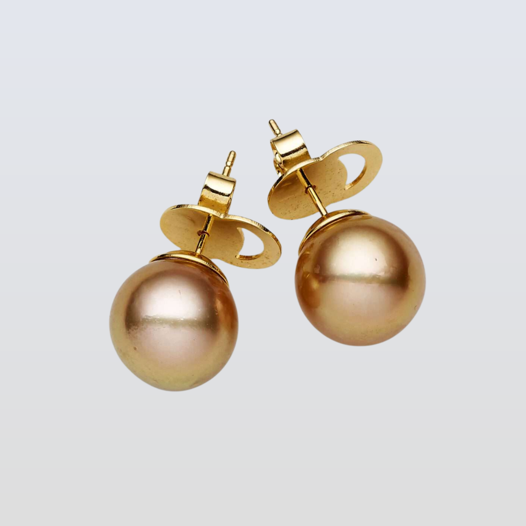 Gold pearl earrings on a light gray background