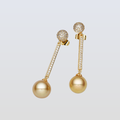 Gold earrings with spherical beads and diamond accents on a light gray background