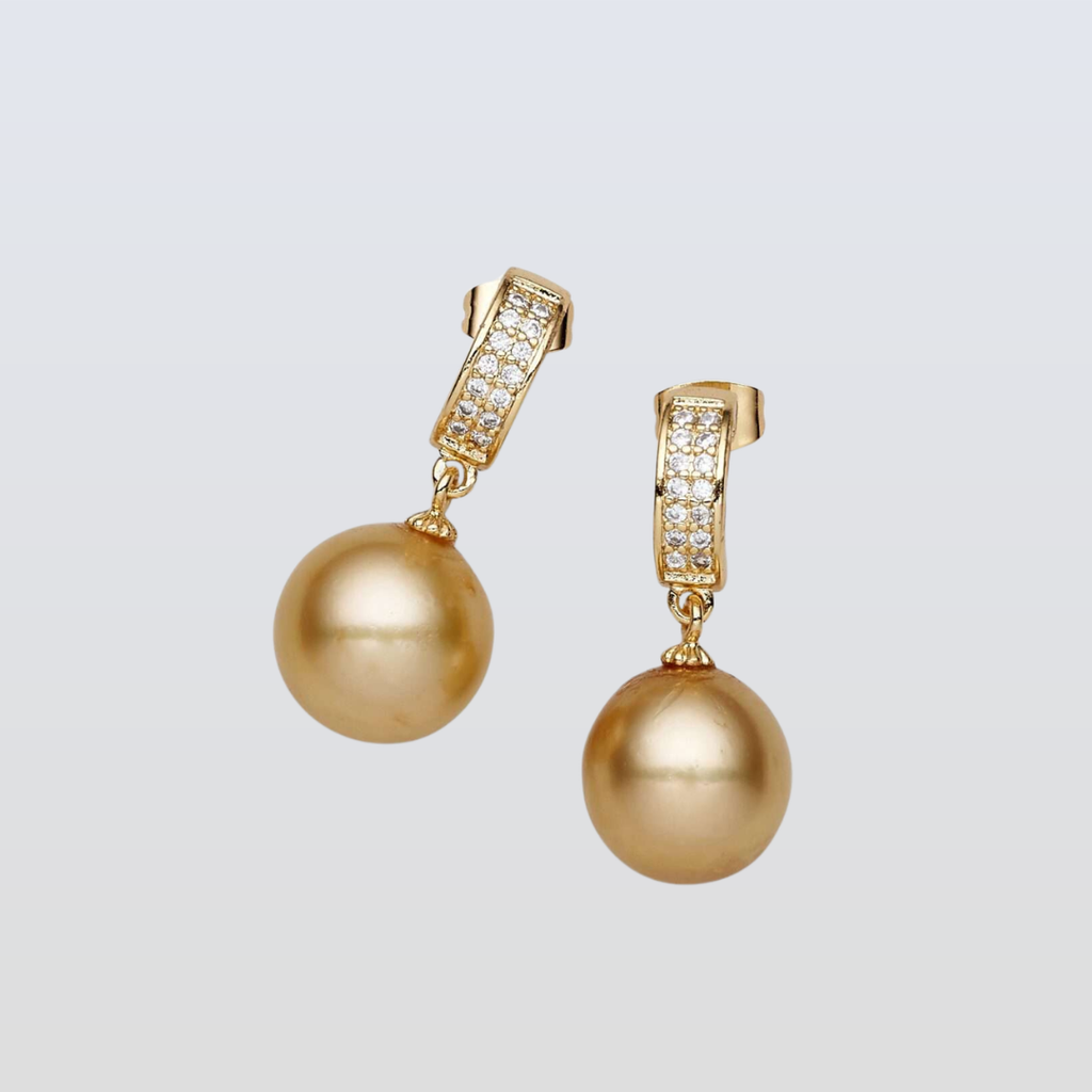 Gold pearl earrings with gold hooks on a light gray background