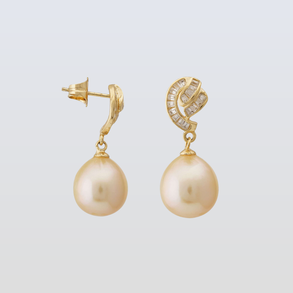 Gold earrings with pearl drops on a light gray background