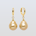 Gold hoop earrings with gold pearls on a light gray background