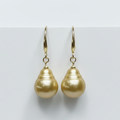 Pair of gold pearl earrings on a light gray background
