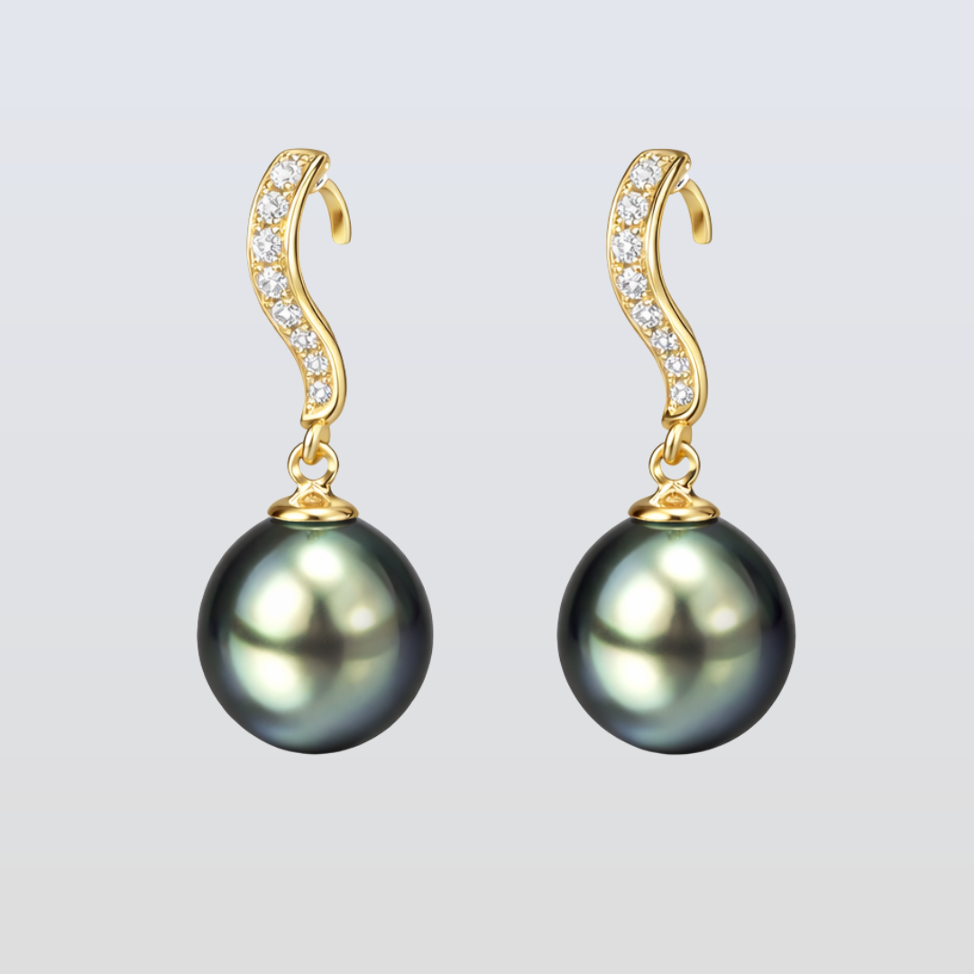 Pair of pearl earrings with gold hooks and diamond accents on a light gray background