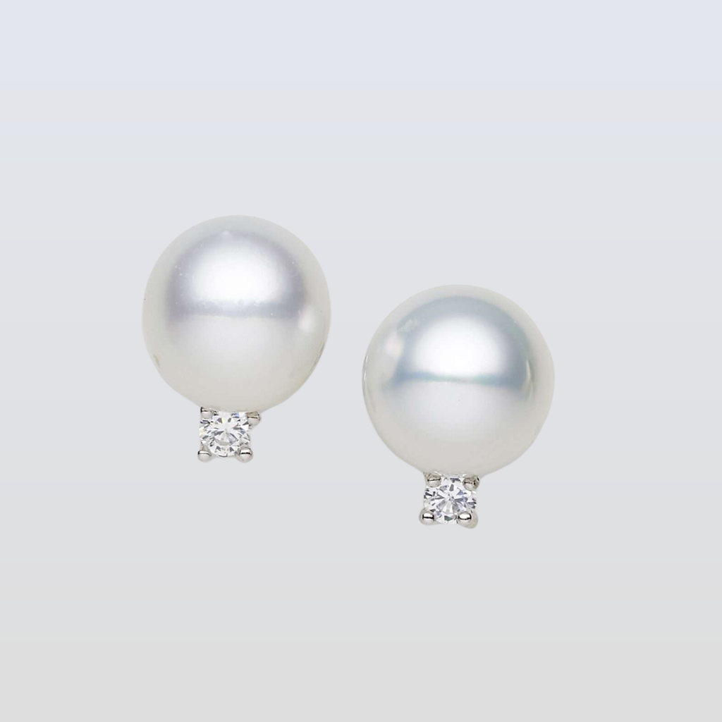 Pearl earrings with diamond accents on a light gray background