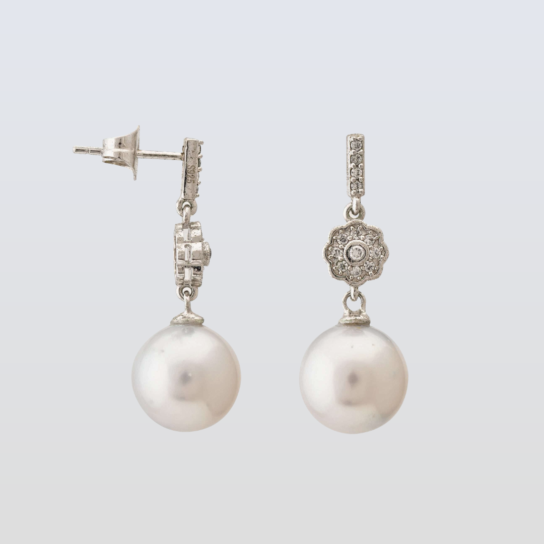Pearl earrings with silver clasps on a light gray background