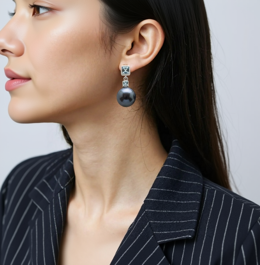 Close-up of a person wearing a black pearl earring with a silver setting.