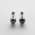 Pair of pearl earrings with blue gemstones on a light gray background