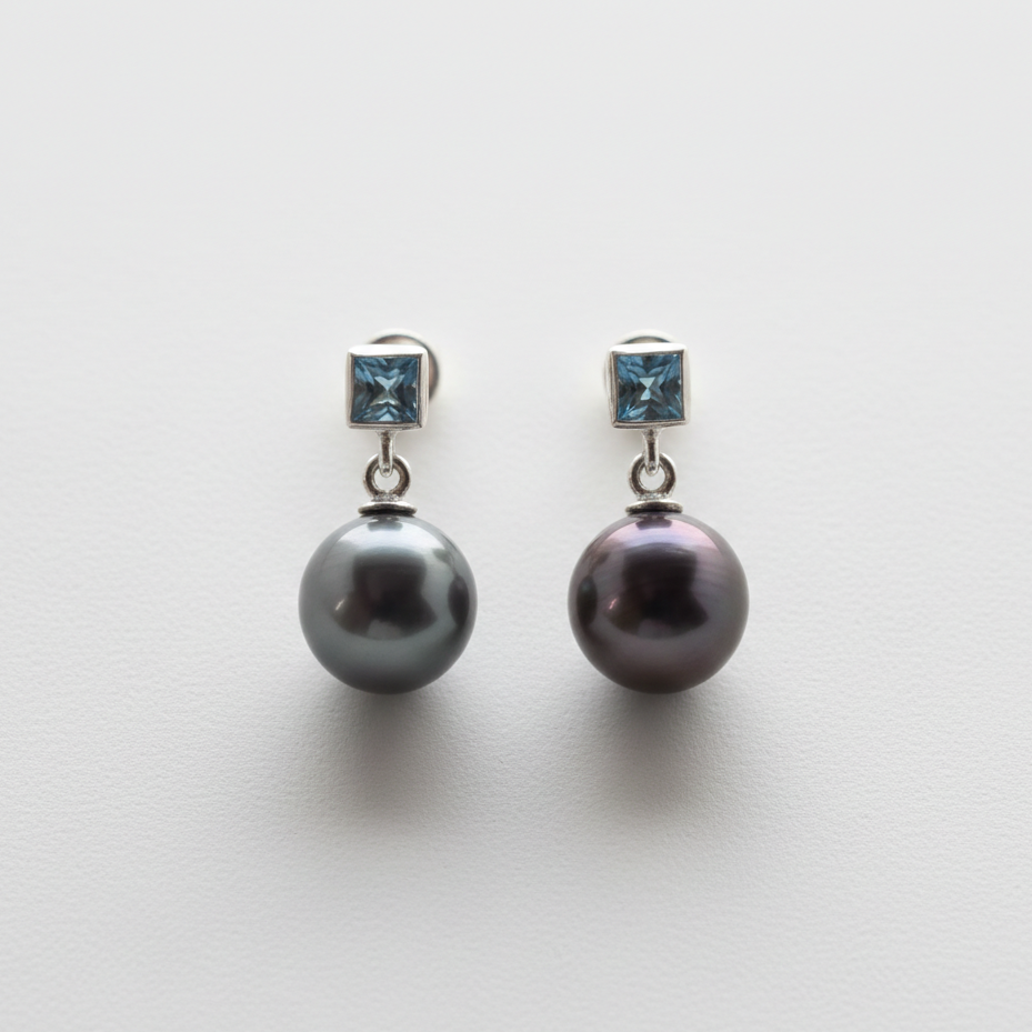Pair of pearl earrings with blue gemstones on a light gray background