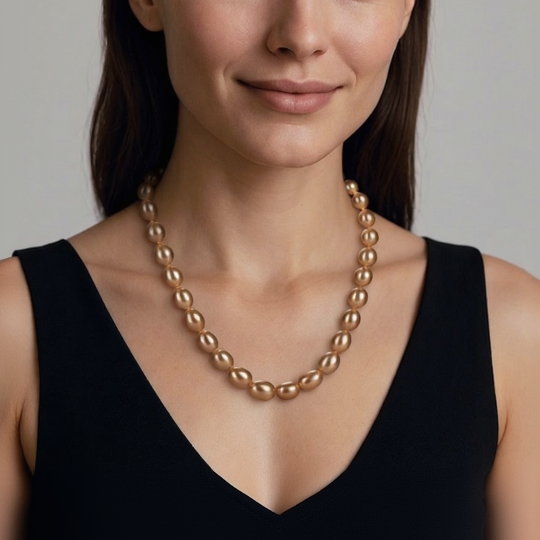 Woman wearing a gold necklace against a neutral background