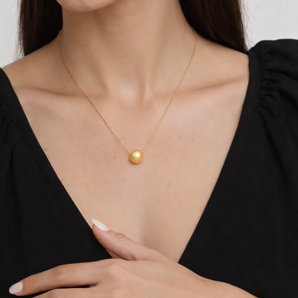 Woman wearing a gold necklace with a pendant on a plain background