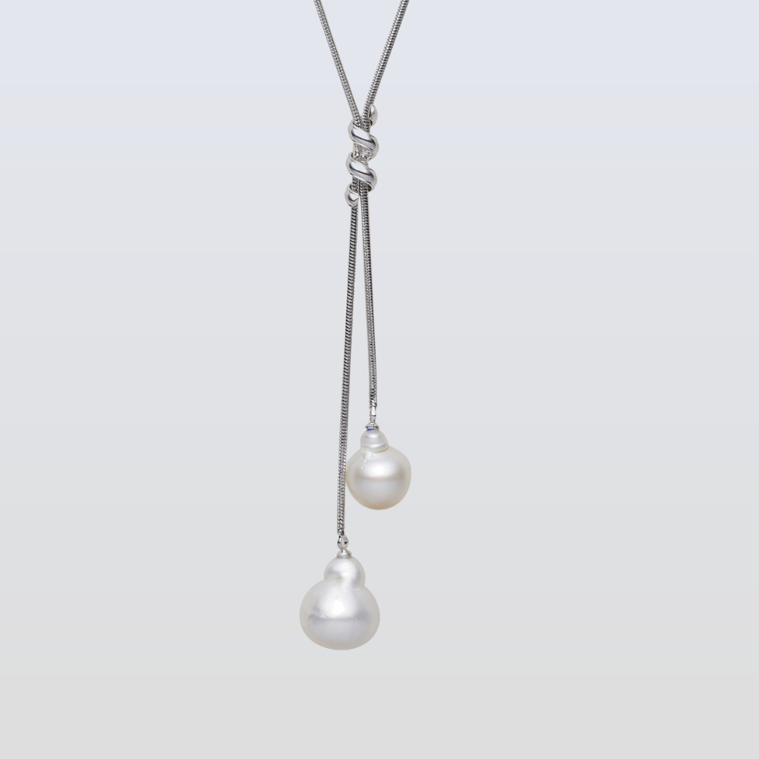 Pearl necklace with two hanging pearls on a light gray background