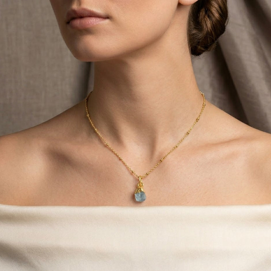 Necklace with a blue gemstone worn by a model against a neutral background