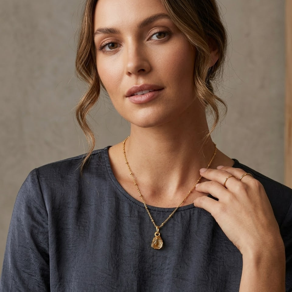 Woman wearing a gold necklace against a neutral background