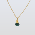 Gold necklace with a green gemstone pendant on a light gray background