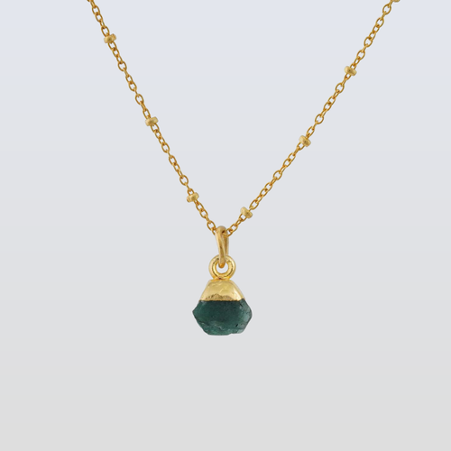 Gold necklace with a green gemstone pendant on a light gray background