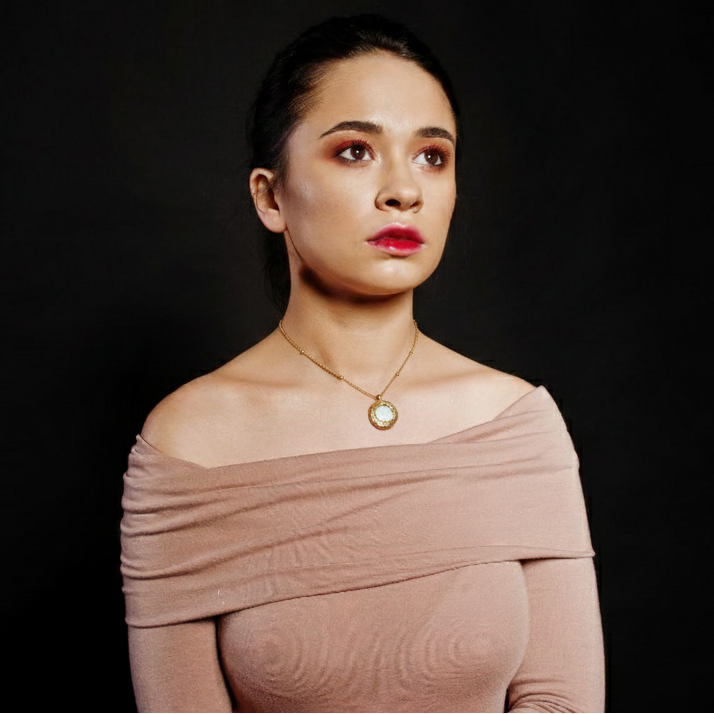 Woman wearing a beige off-shoulder dress against a black background