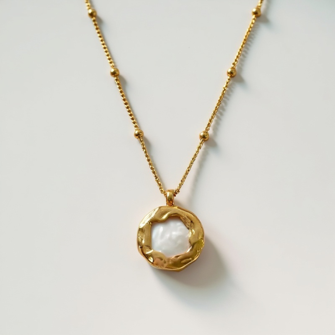 Gold necklace with a circular pendant on a light gray background