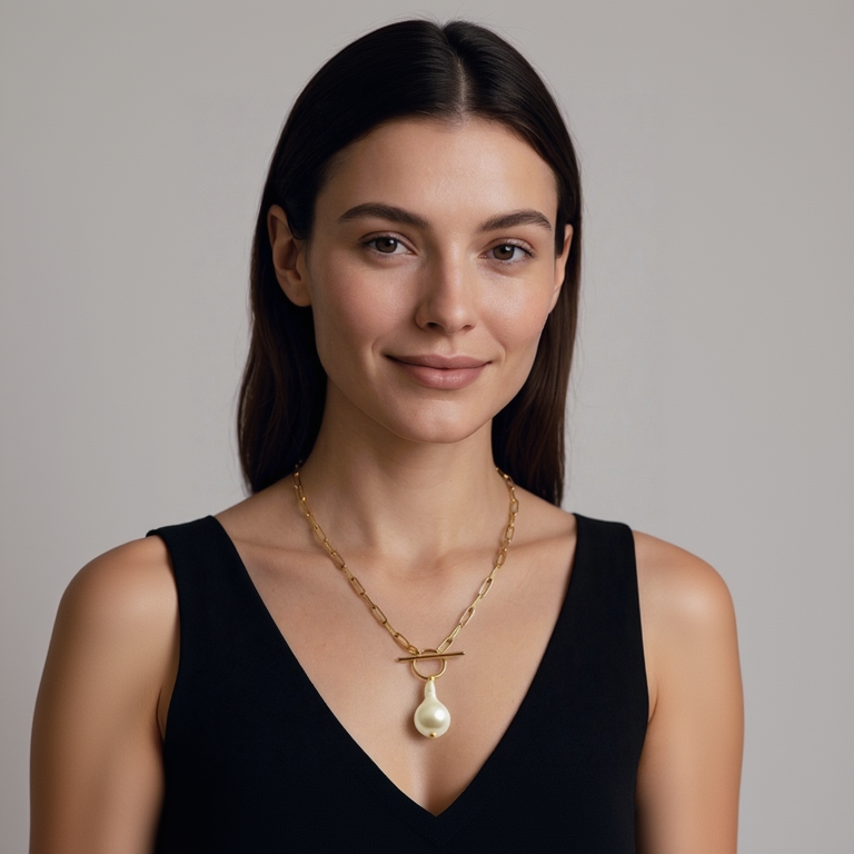 Woman wearing a gold necklace with a pearl pendant against a neutral background
