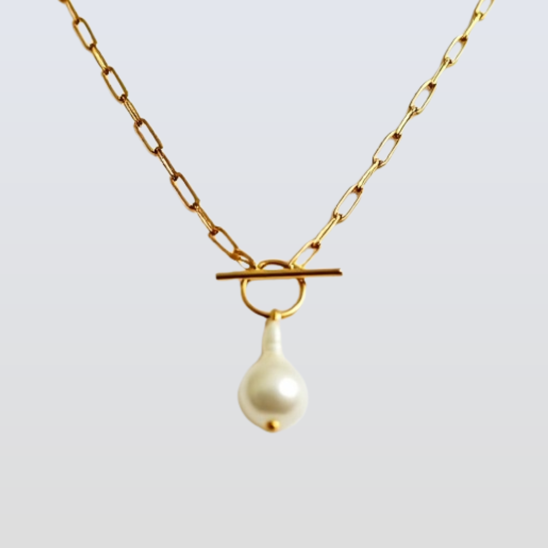 Gold necklace with a white pearl pendant on a light gray background