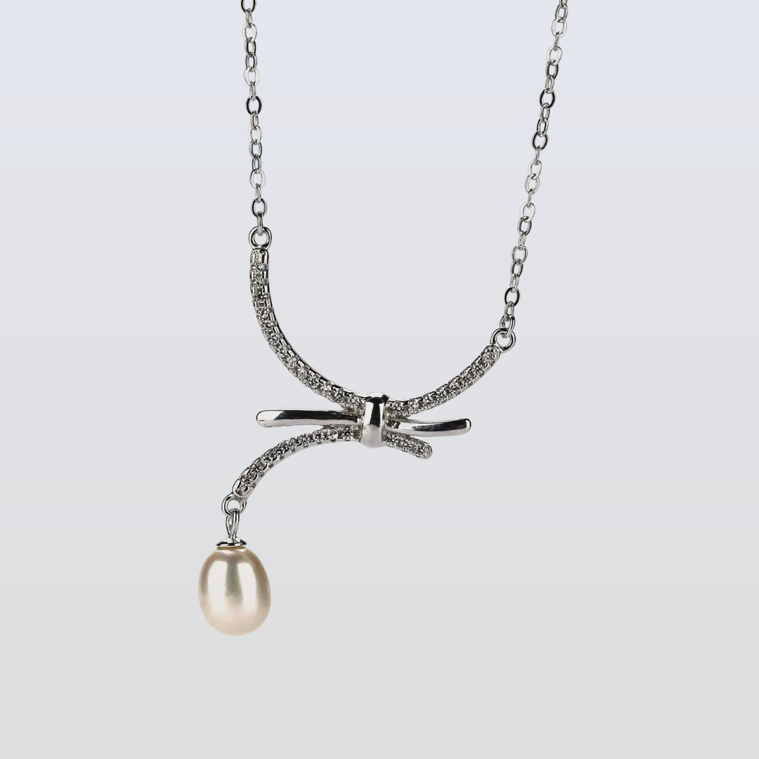 Necklace with a bow and pearl pendant on a light gray background