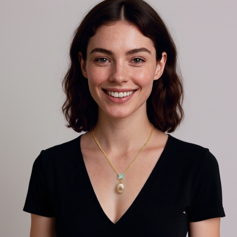 Woman wearing a gold necklace with a pearl pendant against a plain background