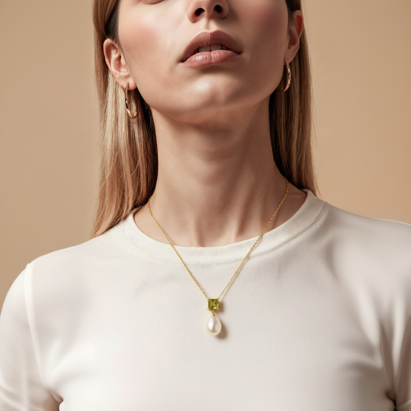 Close-up of a person wearing a gold necklace with a pearl pendant on a beige background