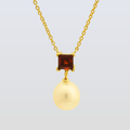 Gold necklace with a square gemstone and round pendant on a light gray background