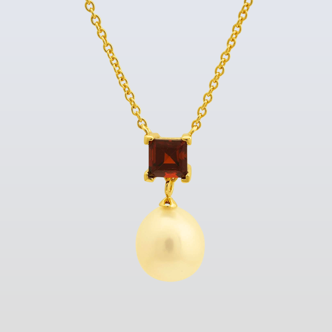 Gold necklace with a square gemstone and round pendant on a light gray background