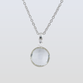 Silver necklace with a round pendant on a light gray background