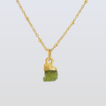 Gold necklace with a green stone pendant on a light gray background