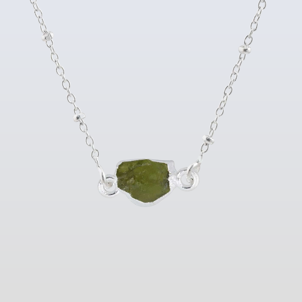 Necklace with a green stone pendant on a light gray background