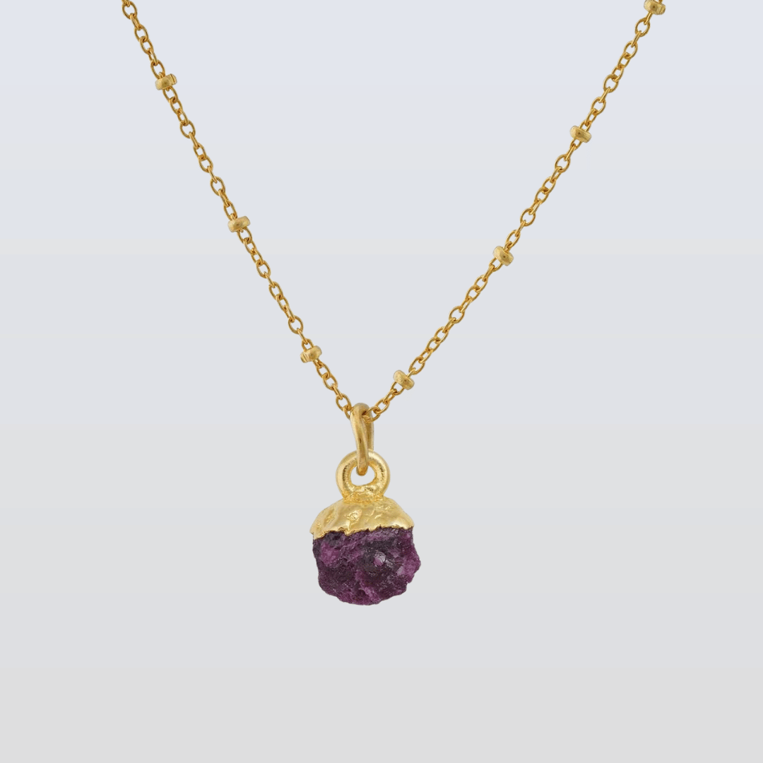 Gold necklace with a purple gemstone pendant on a white background