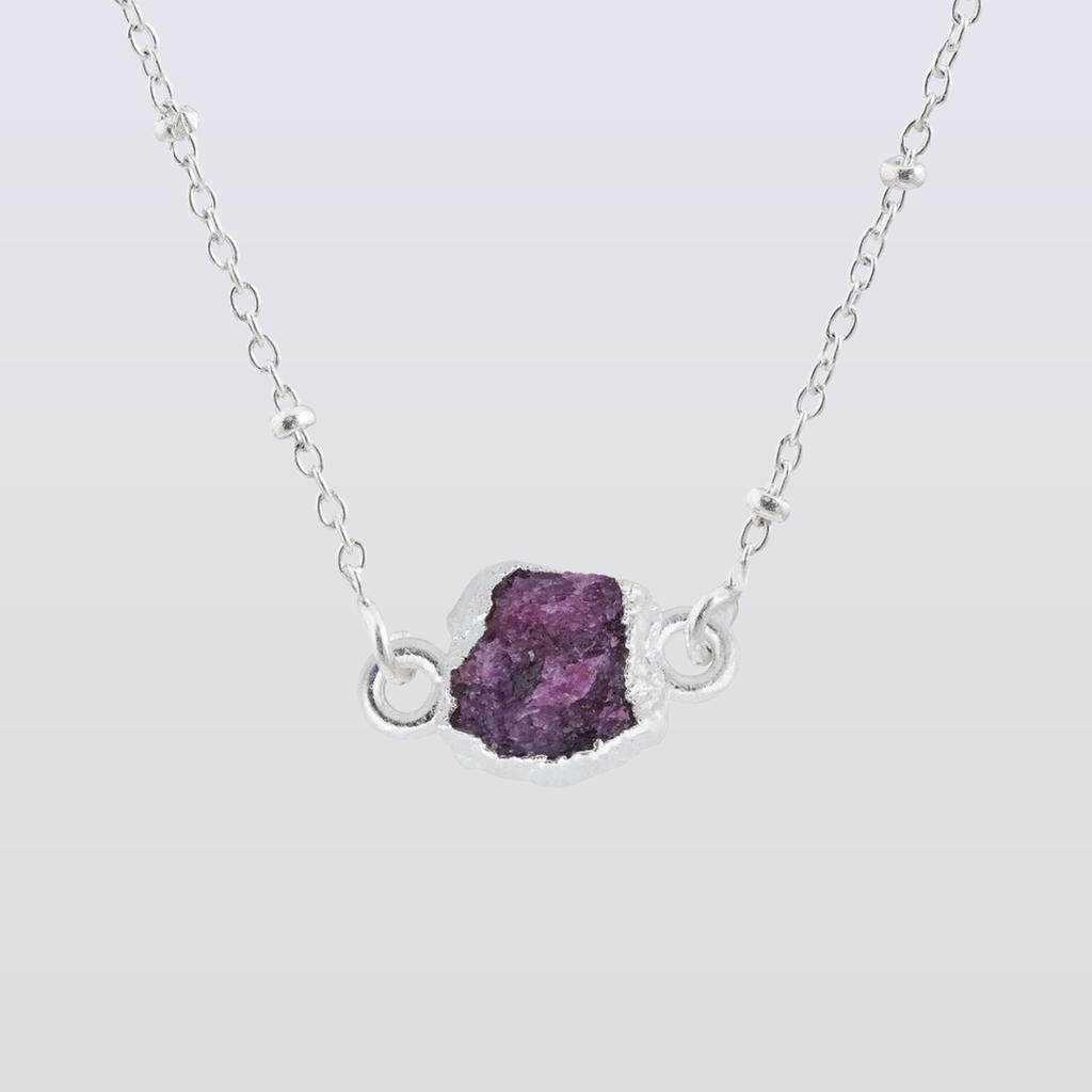 Necklace with a purple gemstone pendant on a light gray background