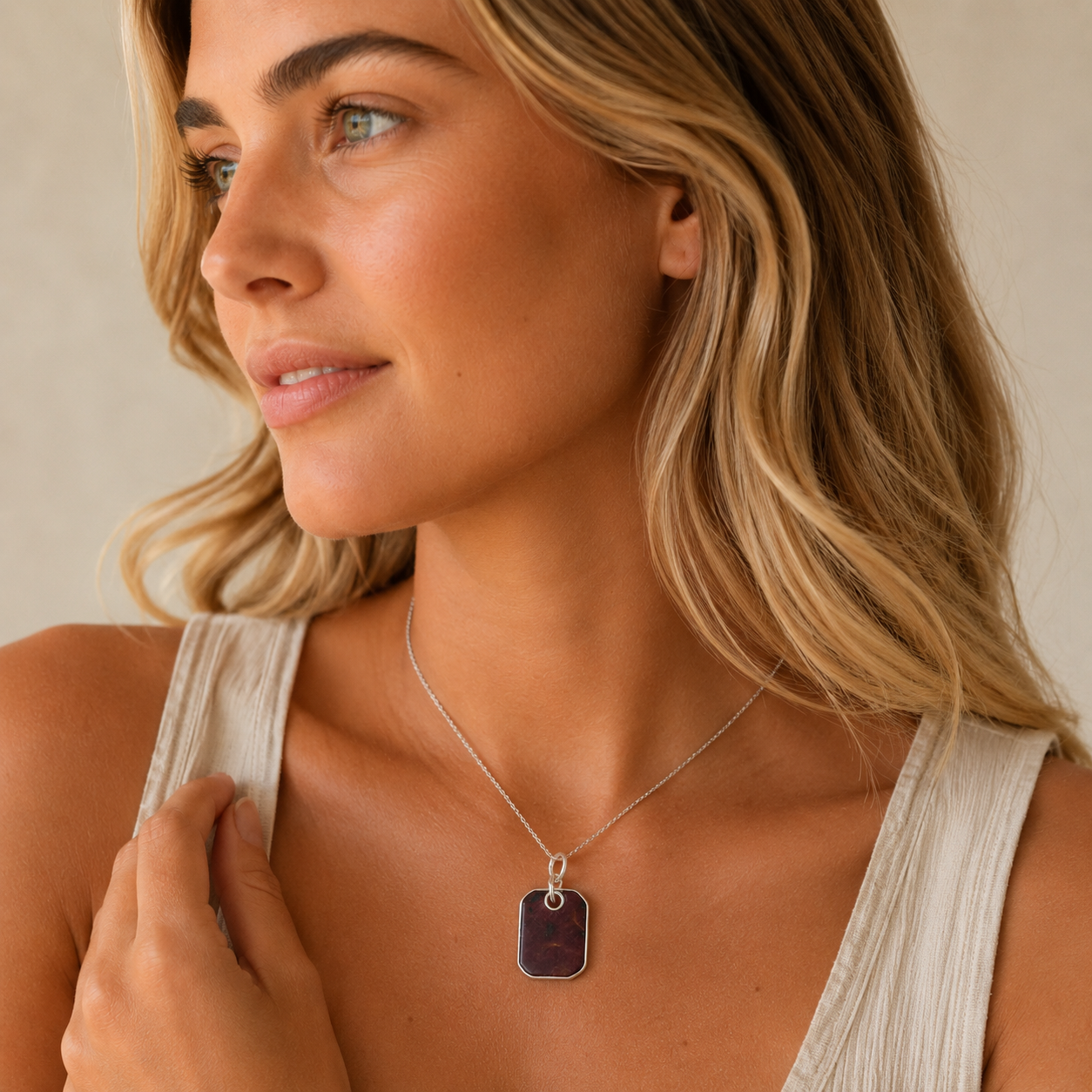 Woman wearing a necklace with a pendant against a neutral background