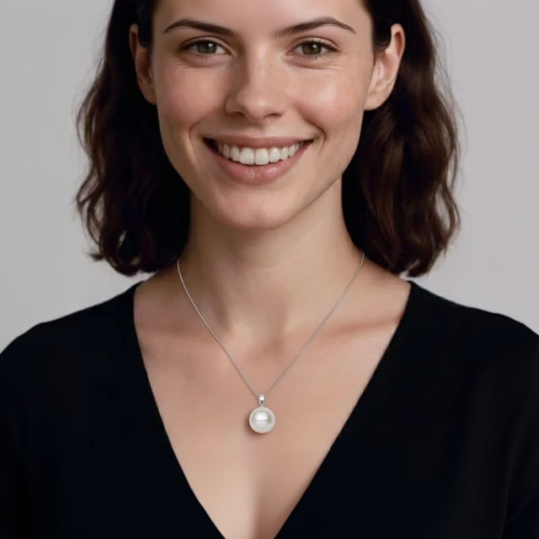 Woman wearing a necklace with a pearl pendant against a plain background