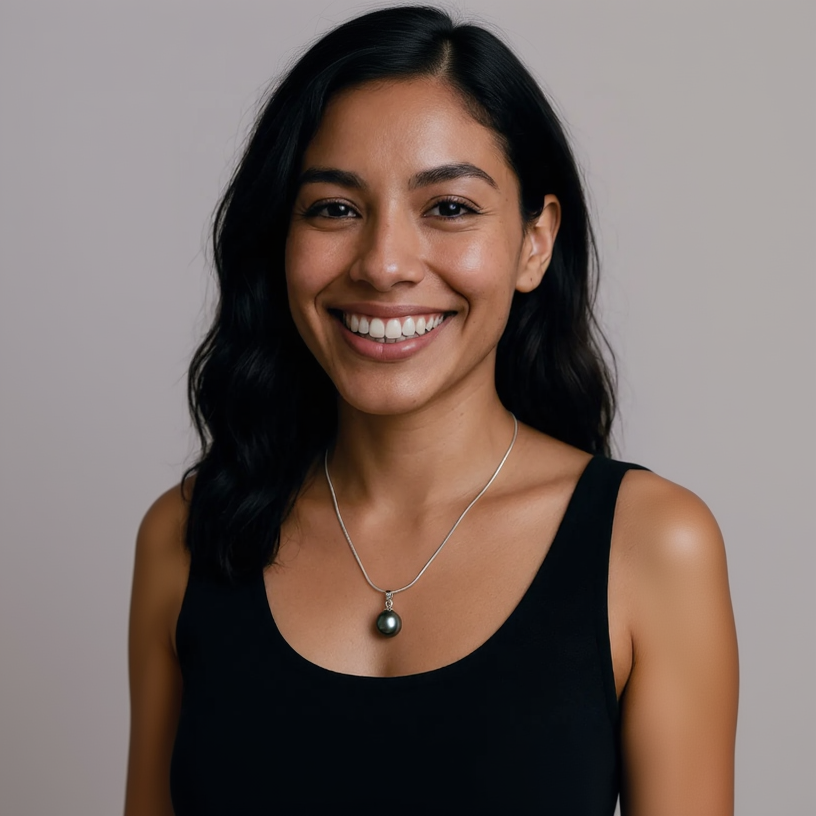 Woman wearing a black top and silver necklace with a pendant against a neutral background