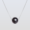 Necklace with a single black pearl on a light gray background