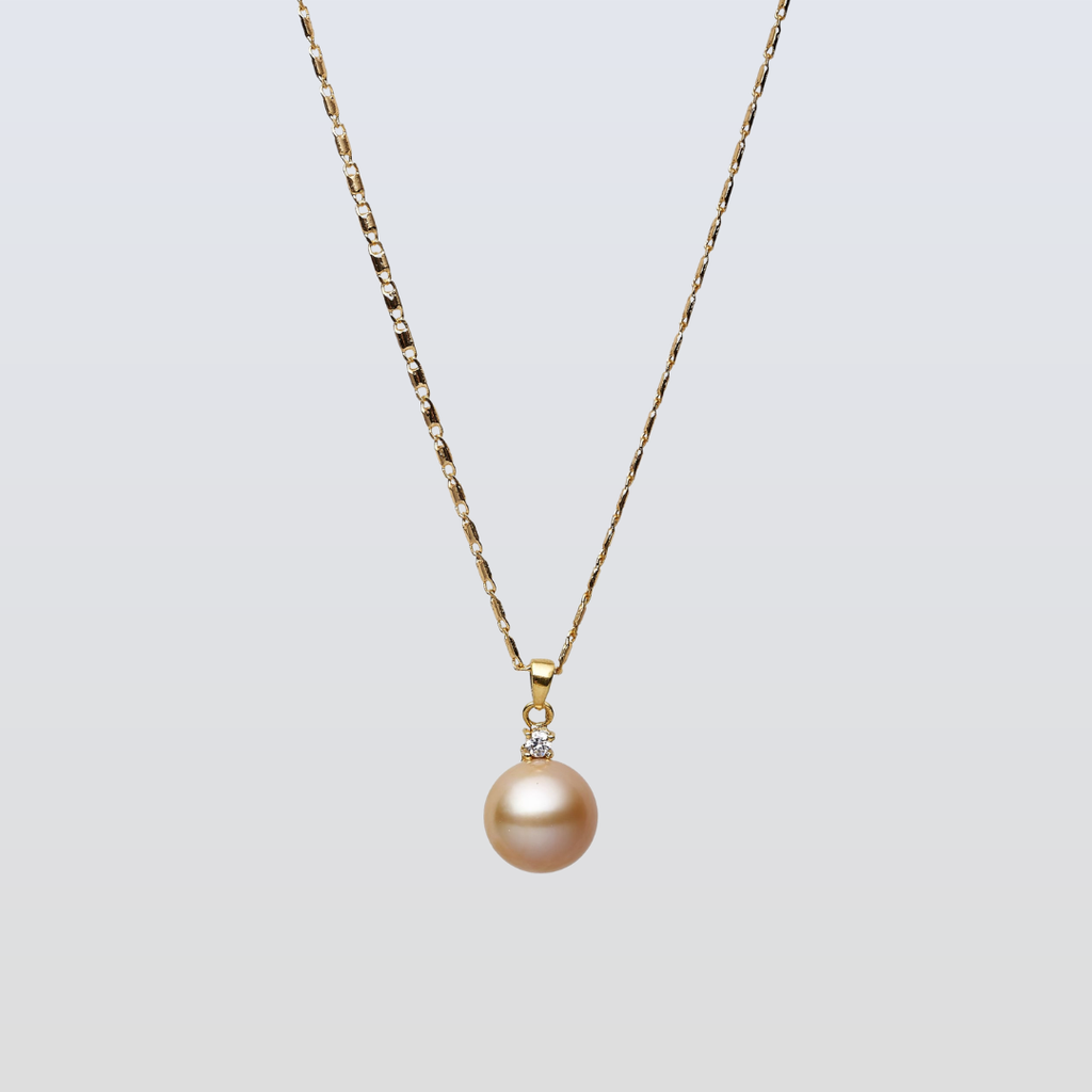 Gold necklace with a single pearl pendant on a light gray background