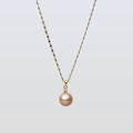 Gold necklace with a single pearl pendant on a light gray background