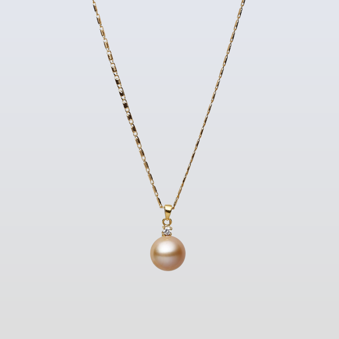 Gold necklace with a single pearl pendant on a light gray background