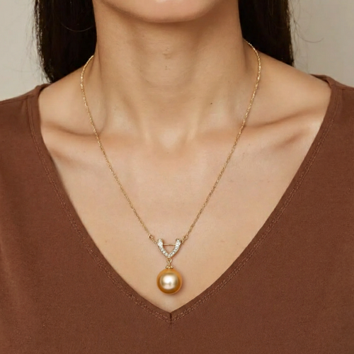 Woman wearing a gold necklace with a pearl pendant on a neutral background