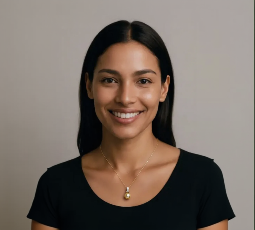 Woman wearing a gold necklace with a pendant against a neutral background