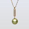 Gold necklace with a green pearl pendant on a light gray background