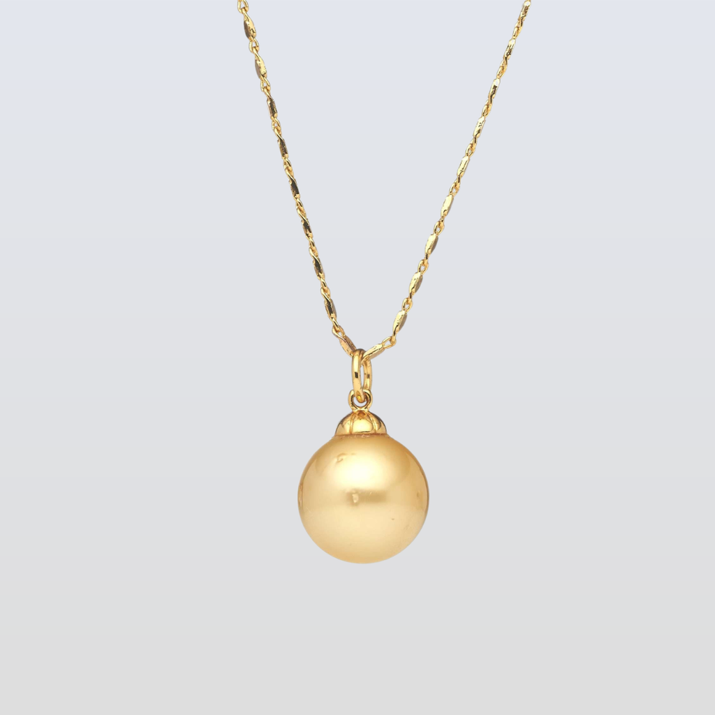 Gold necklace with a round pendant on a light gray background