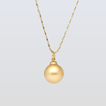 Gold necklace with a round pendant on a light gray background