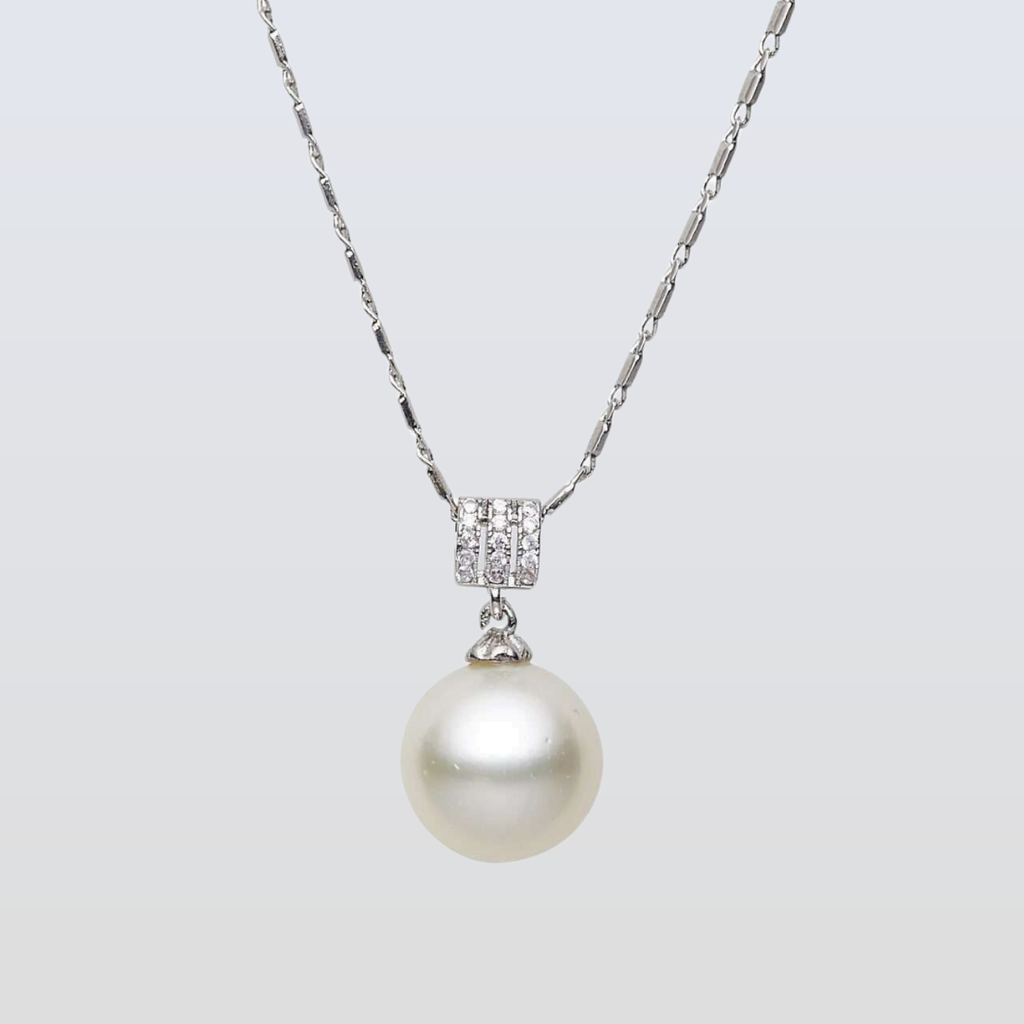 Pearl necklace with a silver chain and clasp on a light gray background
