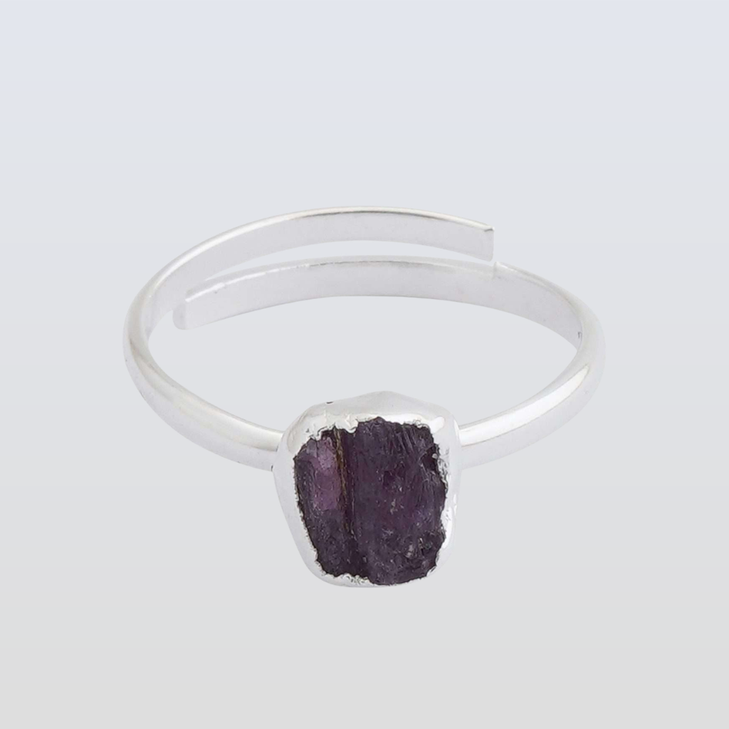 Silver ring with a purple stone on a light gray background