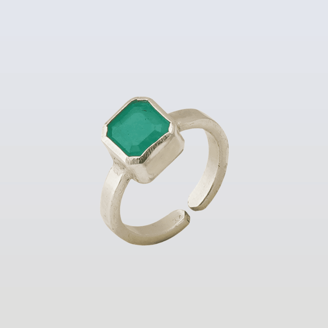 Silver ring with a green gemstone on a light gray background