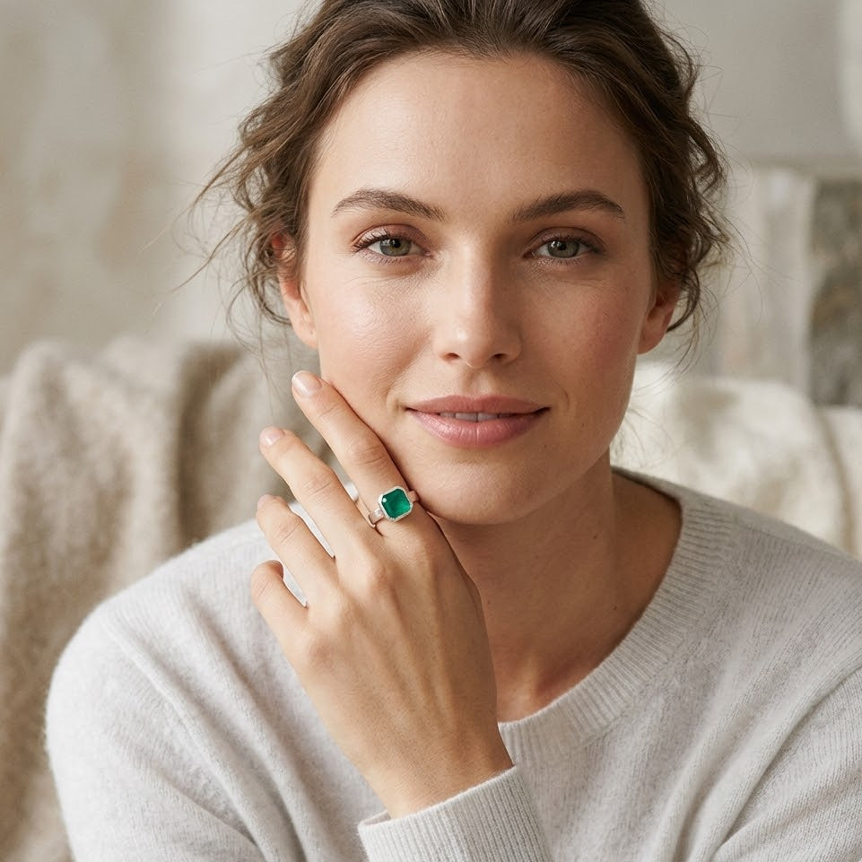 Woman wearing a green ring on her finger, sitting in a cozy indoor setting.